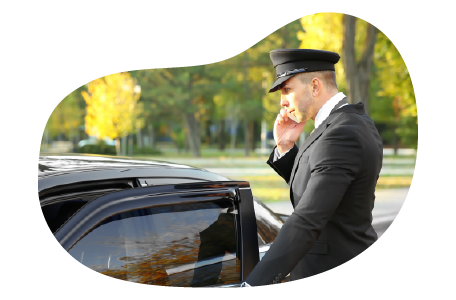 A chauffeur talks on the phone while getting into their limo.