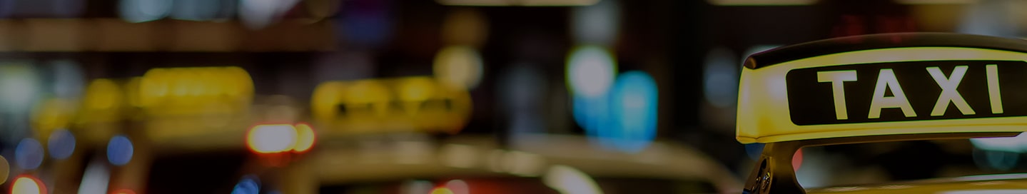 A line of yellow taxis on a city street.