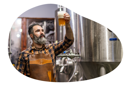 A brewer samples beer from a fermenter. A brewer samples beer from a fermenter.