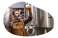 A brewer samples beer from a fermenter.