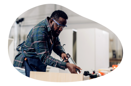 A carpenter uses a caulking gun to seal a cabinet.