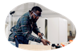 A carpenter uses a caulking gun to seal a cabinet.