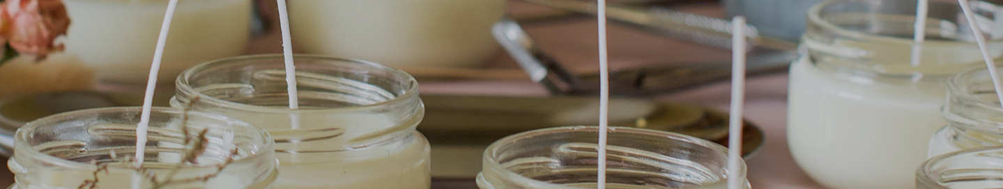 A batch of homemade candles in glass jars.