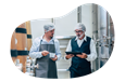 A business owner and an employee evaluate a wine sample in a winery's fermentation cellar.