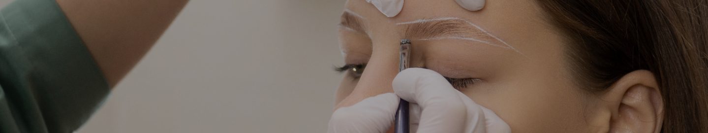 A brow and lash technician sculpts a client's eyebrows.