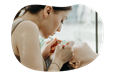 A brow and lash technician works on a client with tweezers.