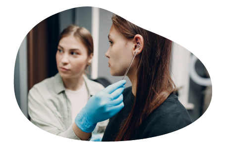 A body piercer prepares a client in a piercing shop. A body piercer prepares a client in a piercing shop.