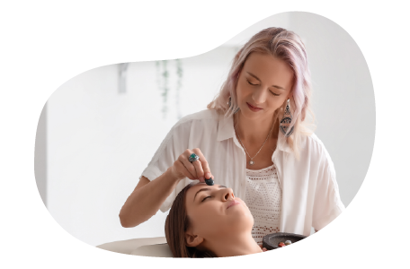 A Reiki practitioner places a healing stone on a client's forehead.