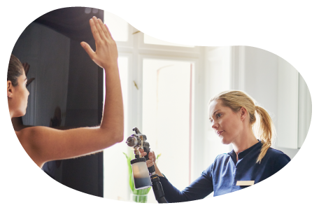 A technician gives an airbrush tan to a client at a tanning salon.