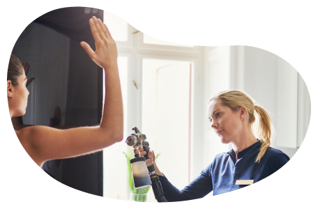 A technician gives an airbrush tan to a client at a tanning salon. A technician gives an airbrush tan to a client at a tanning salon.