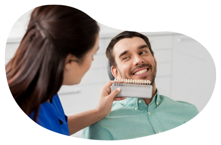 A dental assistant shows a client a tooth shade guide as part of a teeth whitening procedure. A dental assistant shows a client a tooth shade guide as part of a teeth whitening procedure.