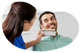 A dental assistant shows a client a tooth shade guide as part of a teeth whitening procedure.