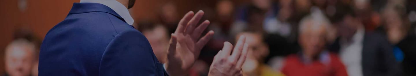 Public speaker in front of a large room of people.