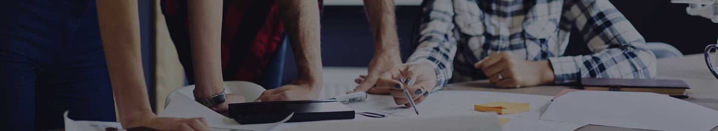 Three people gathered around a table looking at paperwork.