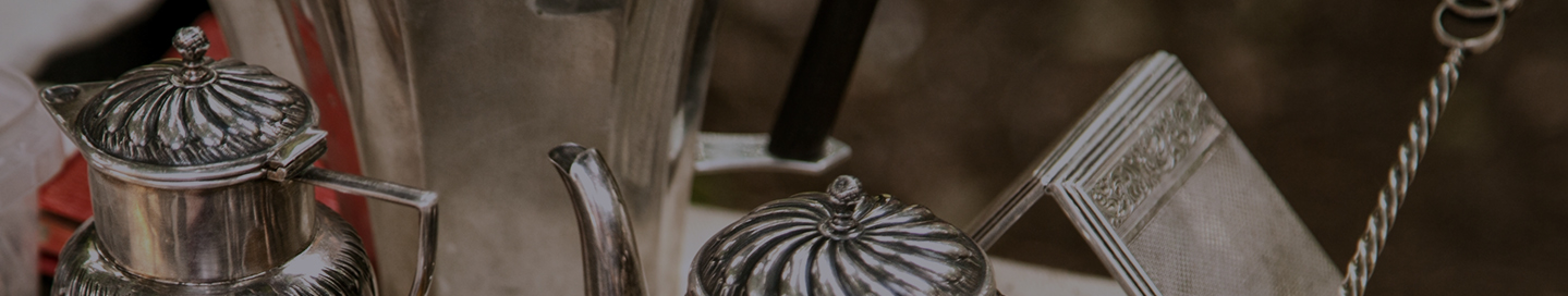 A silver pot and other items for sale in an antique shop.