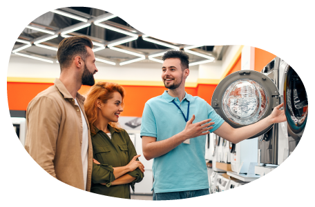 An employee at an appliance store shows off a dryer to customers. An employee at an appliance store shows off a dryer to customers.