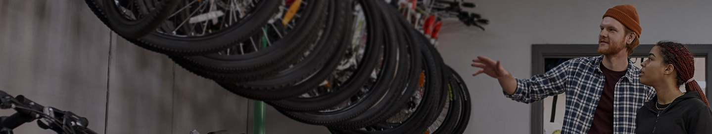 An employee at a bike store shows a selection of mountain bikes to a customer.
