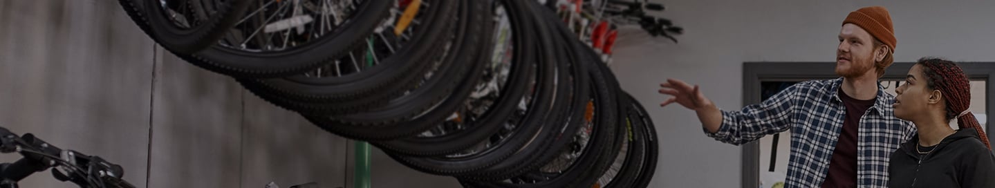 An employee at a bike store shows a selection of mountain bikes to a customer. An employee at a bike store shows a selection of mountain bikes to a customer.