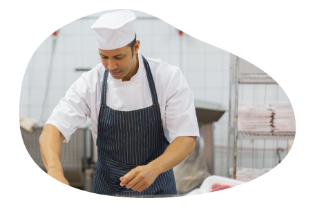 A butcher in an apron cutting up meat.