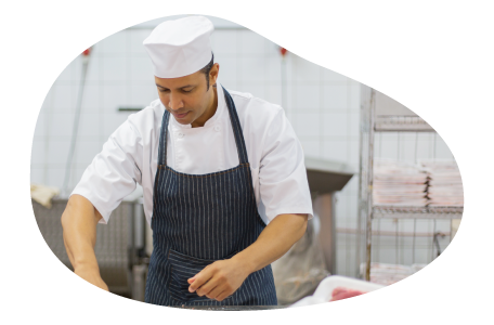 A butcher in an apron cutting up meat. A butcher in an apron cutting up meat.