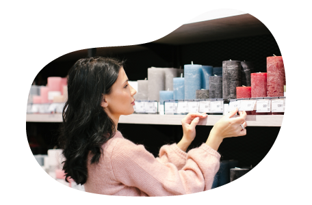 Candle shop employee placing pricing on a store shelf holding candles. Candle shop employee placing pricing on a store shelf holding candles.