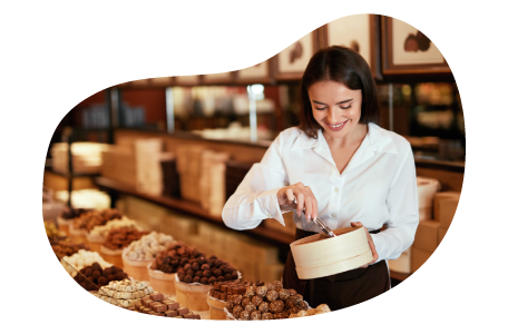 Candy store employee stocking front case in a shop.