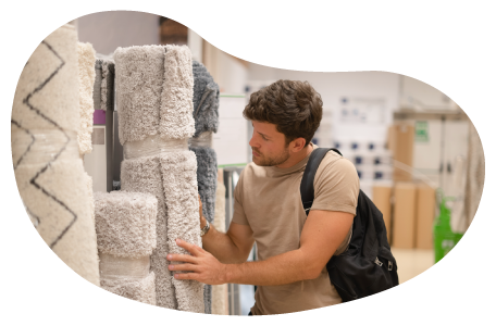 A customer examines a rolled up carpet at a store.