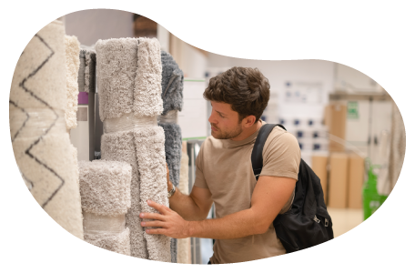 A customer examines a rolled up carpet at a store. A customer examines a rolled up carpet at a store.