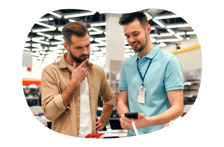 A cell phone store owner showing new features on a smartphone to a customer