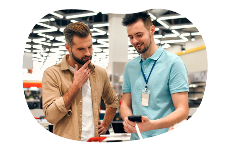A cell phone store owner showing new features on a smartphone to a customer A cell phone store owner showing new features on a smartphone to a customer