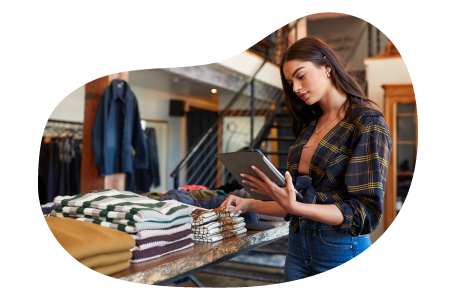 Clothing store employee taking inventory of shirts on a table.