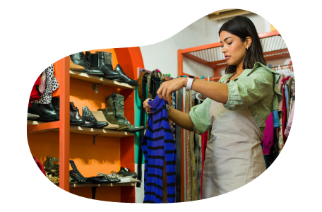 Thrift store employee hanging up new donations on a rack.