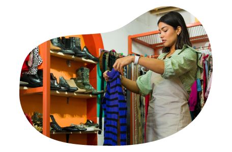 Thrift store employee hanging up new donations on a rack. Thrift store employee hanging up new donations on a rack.