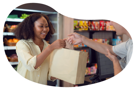 A cashier hands a paper bag to a customer at a convenience store.