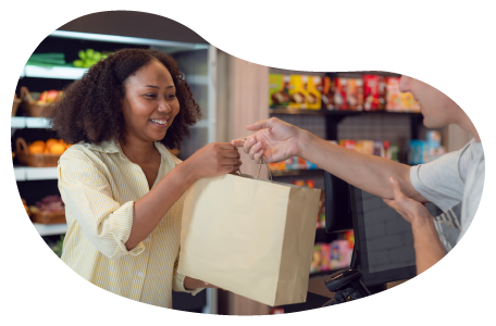 A cashier hands a paper bag to a customer at a convenience store. A cashier hands a paper bag to a customer at a convenience store.