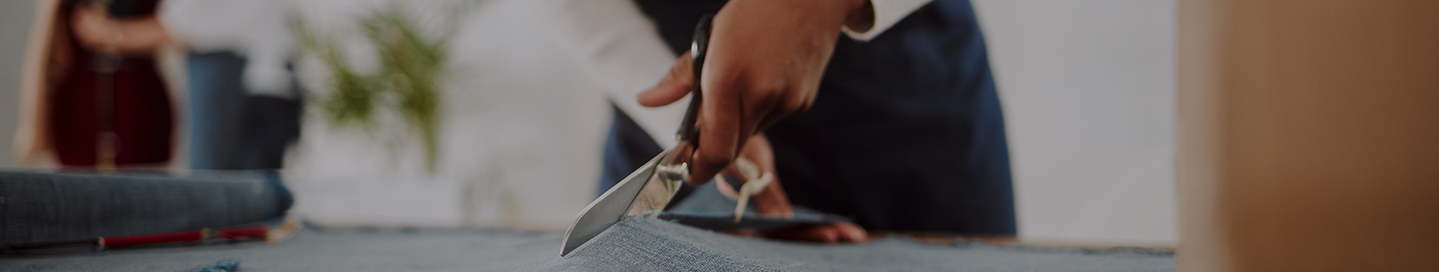 An employee at a fabric store cuts a length of fabric.