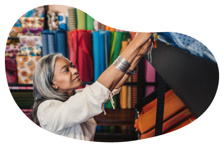 The owner of a fabric store examines a bolt of fabric.