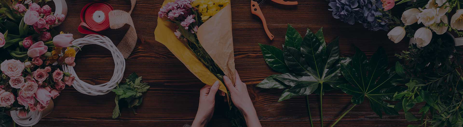 Cropped image of florist wrapping bouquet in pack paper in shop. Cropped image of florist wrapping bouquet in pack paper in shop.