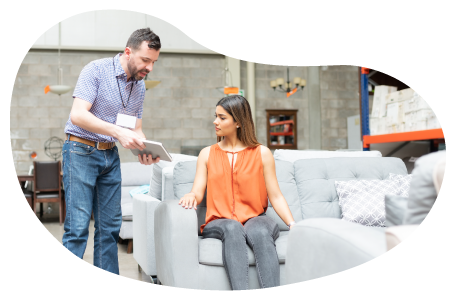 Furniture store employee showing different options on a tablet to a customer on a couch.
