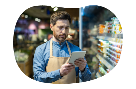 The owner of a general store checks a list of products on a tablet.