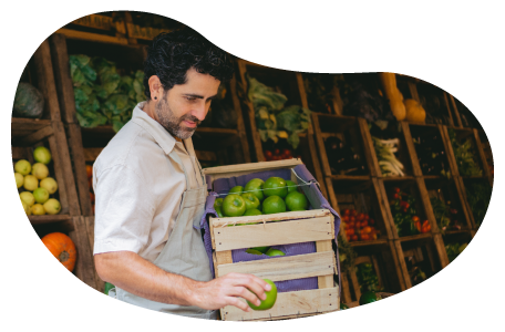 Grocery store employee stocking a produce shelf.