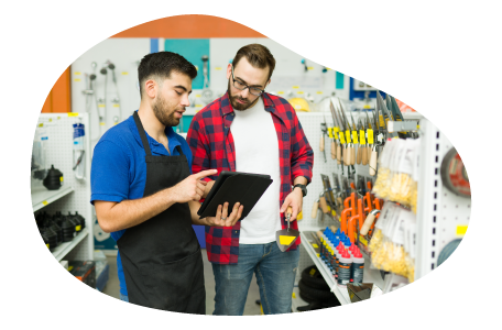 An employee helps a customer find the right item at a hardware store. An employee helps a customer find the right item at a hardware store.