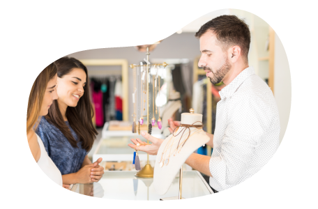 Jewelry store employee helping a customer try on rings.