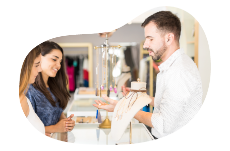 Jewelry store employee helping a customer try on rings. Jewelry store employee helping a customer try on rings.