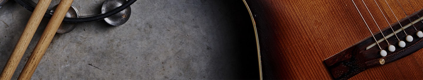 Close-up of drumsticks, a tambourine, and a guitar.