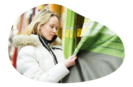 A customer examines curtains in a window shade and curtain store.