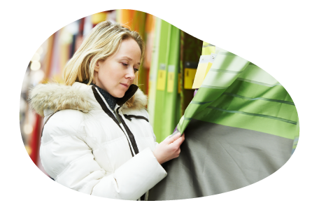 A customer examines curtains in a window shade and curtain store. A customer examines curtains in a window shade and curtain store.