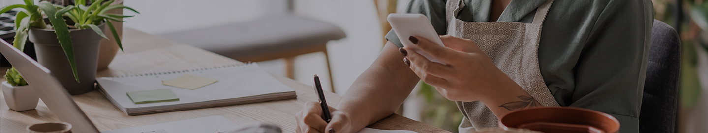 A Shopify seller copies info from their phone into a notebook.