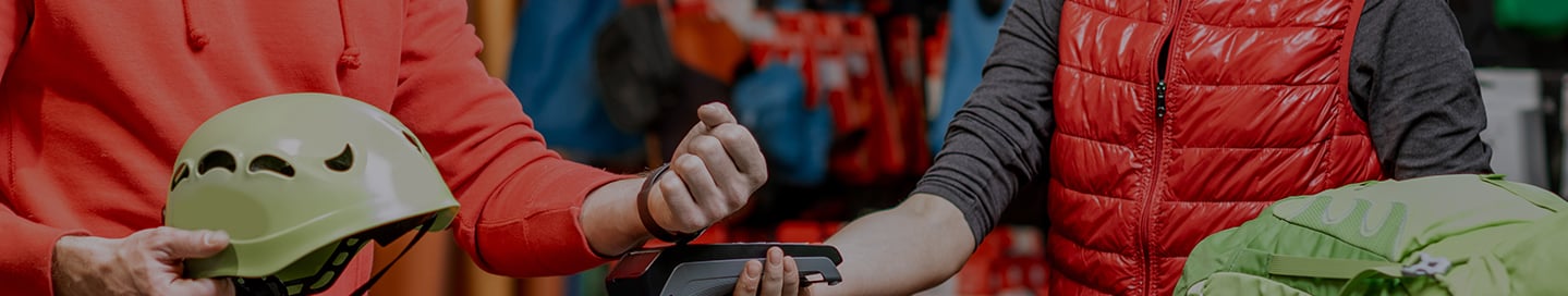 A sales clerk sells a bike helmet to a customer in a sporting goods store. A sales clerk sells a bike helmet to a customer in a sporting goods store.