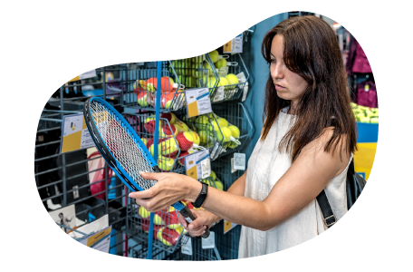 A customer examines a tennis racket at a sporting goods store.